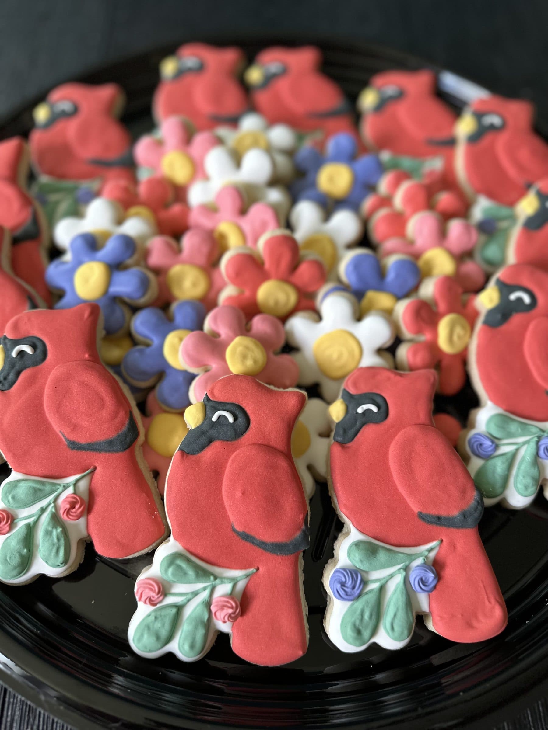 Red cardinal cookies with flower and holly cookies on a round platter