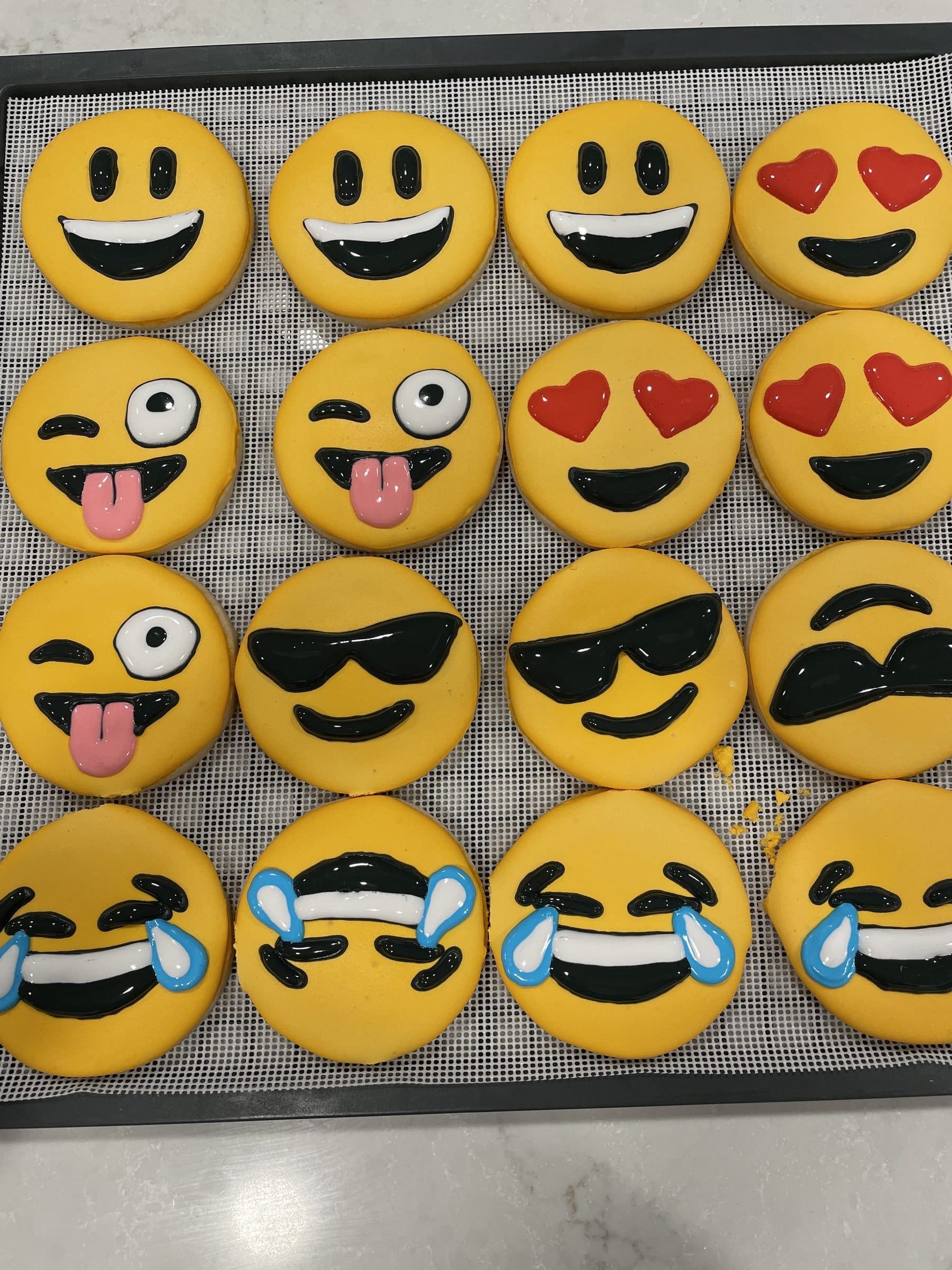 Rows of smiley-face emoji cookies with heart eyes, sunglasses, and tears of joy